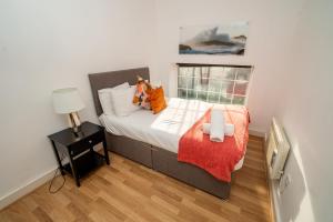 a bedroom with a bed with an orange blanket at Cozy and Modern 2-bed apartment in Swansea
