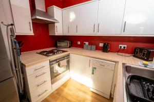 a small kitchen with white cabinets and red walls at Cozy and Modern 2-bed apartment in Swansea +31 photos