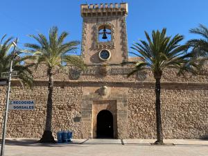 un edificio con una torre de reloj y palmeras en Tres Sol Apartamento, en Santa Pola