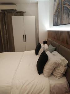 a bed with white pillows and black pillows at Bark Luxury Apartments @The Signature in Accra