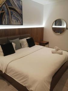 a large white bed in a room with a mirror at Bark Luxury Apartments @The Signature in Accra