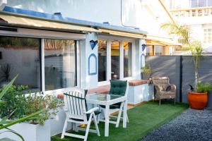 a small patio with a table and chairs on grass at Appartement avec piscine et jacuzzi à 50mètres de la plage et 5min de l'allée des Pins in Argelès-sur-Mer
