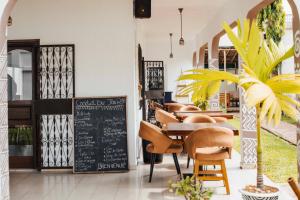 ein Restaurant mit Tisch, Stühlen und einer Tafel in der Unterkunft Villa Kalm in Abidjan