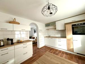 uma cozinha com armários brancos e luz pendente em COVE Appart em Hard