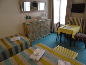 a room with two beds and a table and a table and chair at Hotel California in Vichy