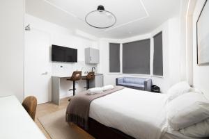 a white bedroom with a bed and a desk at Luxurious London Studios in Harrow