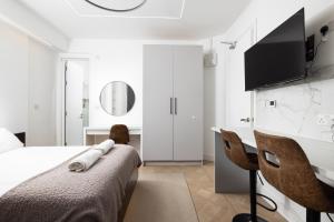 a white bedroom with a bed and a desk at Luxurious London Studios in Harrow