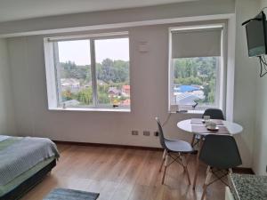 a bedroom with a table and chairs and a window at Departamento Los Carrera Centro in Osorno