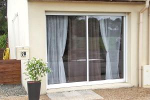 a window with white curtains on a house at Studio confortable à Pédernec - 27m² - Terrasse ensoleillée in Pédernec +5 photos