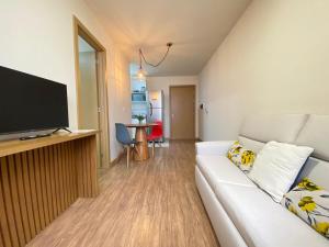 a living room with a white couch and a flat screen tv at Centro, Ar Cond, WI-FI and Lava e Seca in Santa Maria