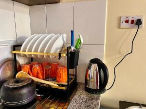 a kitchen with a shelf with plates and utensils at Bella Homes Thika Town Studio in Thika
