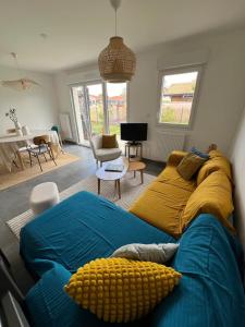 a living room with a blue couch and a yellow blanket at Petite maison cosy avec jardin in Gujan-Mestras