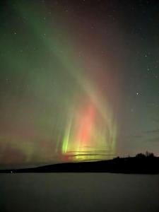 una aurora en el cielo sobre un cuerpo de agua en Villa Niva, en Rovaniemi