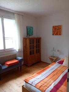 a bedroom with a bed and a chair and window at Large house with large garden in Lauterach