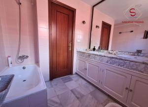 un bagno con due lavandini, una vasca e un grande specchio di Casa Hermosilla con piscina by Sanlúcar Housing a Sanlúcar de Barrameda Altre 40 foto