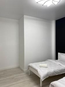 a white bedroom with two beds and a chandelier at Шикарный Гостевой Guest Аpartments MURAGER in Astana