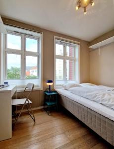 a bedroom with a large bed and two windows at Sleep well in Cozy hideout - Bryggen across the bay in Bergen