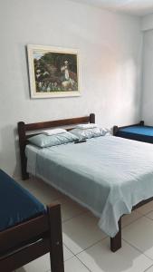 a bed in a bedroom with a painting on the wall at Pousada Alto Mar in Matinhos