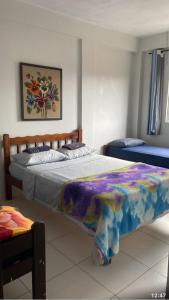 a bedroom with a large bed with a colorful blanket at Pousada Alto Mar in Matinhos