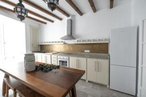a kitchen with white cabinets and a wooden table at El Palacio del Viento Apartamentos in Tarifa