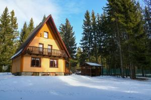 a yellow house with a balcony in the snow at Chata Slávka in Štrba
