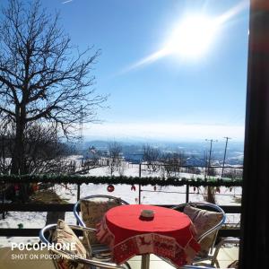 a table and chairs with a red table and snow at Harmonija - Jasenica in Valjevo