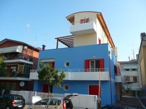 卡奧萊的住宿－Residence Orate - Agenzia Cocal，一座蓝色和白色的建筑,前面有汽车停放