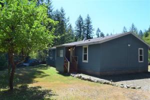a blue tiny house in the middle of a yard at Rustic Rapids · Wood Stove, Creek, Sauna in Packwood