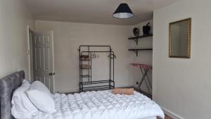 ダラムにあるAmani 2-Bed Bungalow - Sleeps 4 - Pet Friendlyの白いシーツと鏡が付いたベッドのある寝室