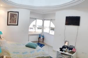 a white room with a bed and a tv at Sea View Apartment in Hammamet with Shared Pool in Hammamet +20 photos