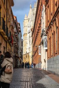 une femme marchant dans une rue pavée avec des bâtiments dans l'établissement MAGIC II a 30 segundos de la Plaza Mayor y 1 minuto de la Catedral, à León