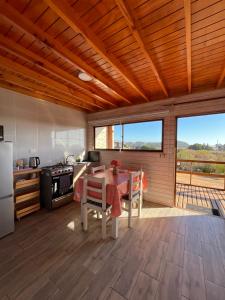 a kitchen with a table and a kitchen with a view at Cabañas Altos de Cahuil in Cáhuil