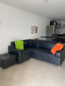 a black leather couch with two green and orange pillows at Alojamiento Armenia in Armenia +9 photos