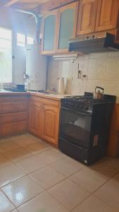 a kitchen with a black stove and wooden cabinets at Departamento Ruca che in Neuquén +7 photos