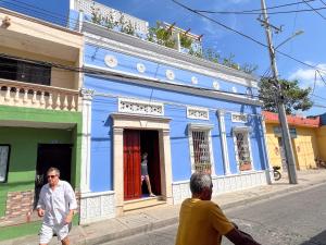 two men walking in front of a blue building at Hotel Casa de la Acequia in Santa Marta