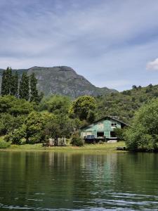 una casa junto a un lago con montañas en el fondo en Lodge Casa de Campo, en Futaleufú