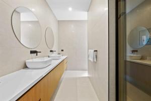 a white bathroom with two sinks and two mirrors at Stunning Beach Side Family Home in St Leonards in Saint Leonards +14 photos