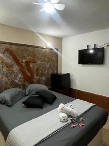 a bedroom with a bed with towels and a flat screen tv at Pousada Familia in Rio das Ostras