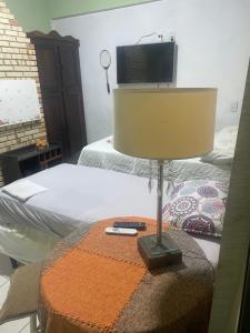 a bedroom with a bed and a tv and a lamp at Trindade encantada in Bombinhas