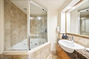 a bathroom with a shower and a sink and a tub at ZANZ205- Exclusive Outdoor Spa with Ocean Glimpses in Mooloolaba