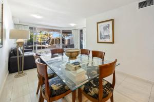 a dining room with a glass table and chairs at ZANZ205- Exclusive Outdoor Spa with Ocean Glimpses in Mooloolaba