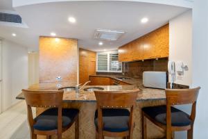 a kitchen with a counter with two bar stools at ZANZ205- Exclusive Outdoor Spa with Ocean Glimpses in Mooloolaba +8 photos
