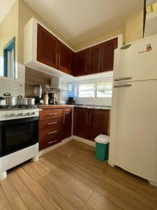 una cucina con frigorifero bianco e armadietti in legno di Casa Aconchego do Mar a Japaratinga