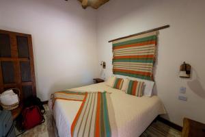 een slaapkamer met een bed met een kleurrijk gestreept kussen bij Hotel Boutique Watungasta in El Puesto