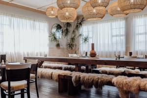 a restaurant with a long table with furry chairs and lights at Lake Mahinapua Hotel in Ruatapu