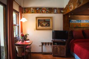 ein Schlafzimmer mit einem Bett und einem Tisch mit einem TV in der Unterkunft Apart del Bosque La Cumbrecita in La Cumbrecita