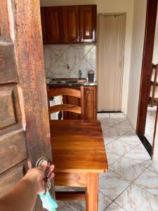 a person holding a chain in a kitchen with a wooden bench at Kitnet Elles in Marau +7 photos