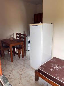 a kitchen with a table and a white refrigerator at Kitnet Elles in Marau