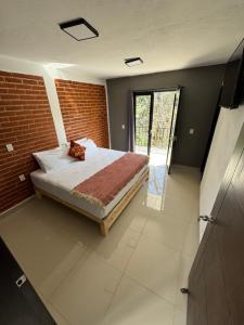 a bedroom with a bed and a brick wall at Casas Victoria in San Cristóbal de Las Casas
