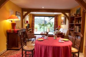 a living room with a table with a red table cloth at Au Fond du Jardin Maison d'hôtes in Saint-Saëns
